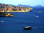 Ein Boot nähert sich Omans felsiger Küste